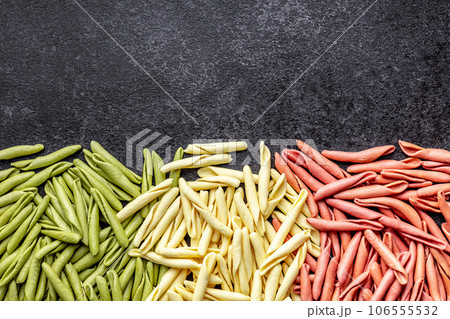 Fusilli pugliesi. Italian tricolor twisted pasta on black table. Top view. 106555532