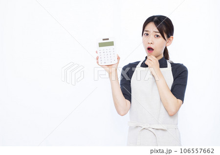 白い背景の前で電卓を持ちおどろく30代の主婦 白い背景の前で電卓を持ちおどろく30代の主婦 106557662