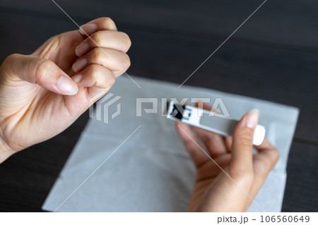 爪切りで爪を切っている若い女性の手元 106560649