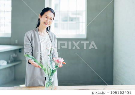 笑顔で花を生けるシニア女性   106562455