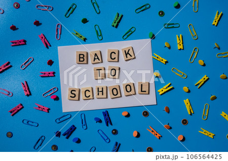 Educational greeting announcement for students and teacher. Saying BACK TO SCHOOL text on wooden blocks on creative vivid background with stationery supplies around. Concept of new school year Educational greeting announcement for students and teacher. Saying BACK TO SCHOOL text on wooden blocks on creative vivid background with stationery supplies around. Concept of new school year 106564425
