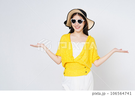 Young woman wearing a sun hat and sunglasses, presenting or showing open hand palm with copy space for product isolated on white background. 106564741