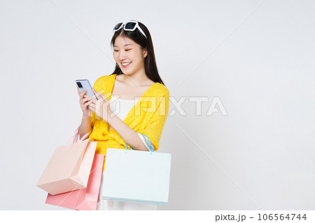 Young woman holding shopping bags while using mobile phone isolated over white background. 106564744