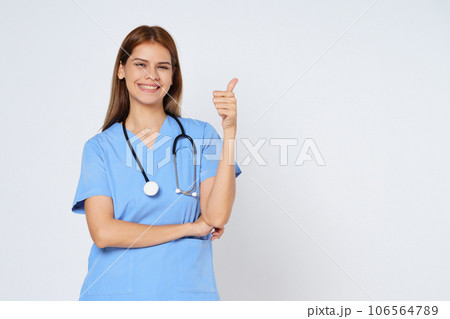 Portrait of smiling young woman doctor with stethoscope showing thumbs up isolate on white background. Portrait of smiling young woman doctor with stethoscope showing thumbs up isolate on white background. 106564789
