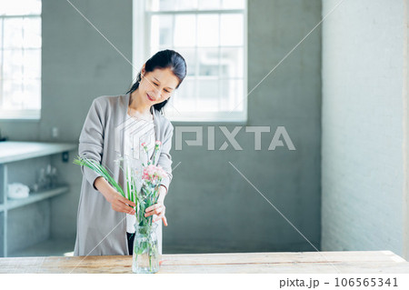 笑顔で花を生けるシニア女性   106565341