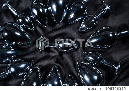 Many metal anal plugs on a black silk sheet. Many metal anal plugs on a black silk sheet. 106566336