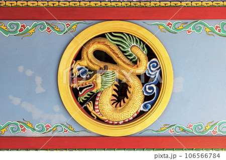 A circular carving of a golden dragon mounted on the shrine's wall symbolizes good luck, power and authority. It is a beautiful work of art that reflects the art and culture of China and East Asia. A circular carving of a golden dragon mounted on the shrine's wall symbolizes good luck, power and authority. It is a beautiful work of art that reflects the art and culture of China and East Asia. 106566784