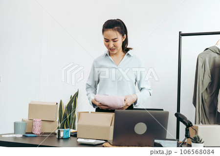 Asian entrepreneur is preparing her clothes that can be sold in paper boxes for delivery to customers. 106568084