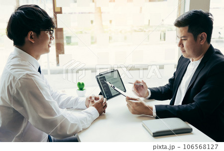 The interview room while the staff is preparing the resume document and presenting to the manager who is talking and analyzing about the work experience. 106568127