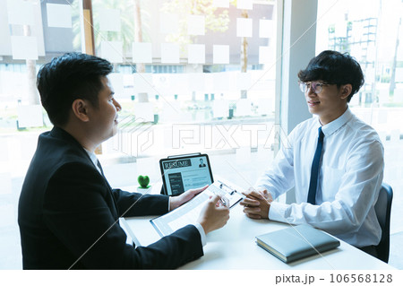 Asian young adult sitting at desk across from manager being interviewed job interview in business room. 106568128