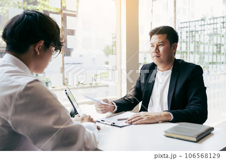 Male manager is talking or explaining about having to dismiss the employee while being handed out a resignation envelope to the employee. 106568129