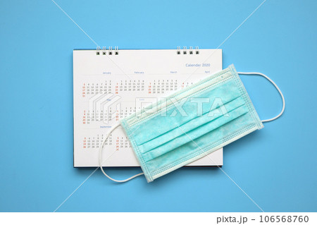 Surgical face mask on 2020 calendar page on blue background Year of Covid-19 Coronavirus prevention concept Surgical face mask on 2020 calendar page on blue background Year of Covid-19 Coronavirus prevention concept 106568760