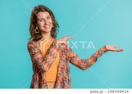 Young woman showing thumbs up and pointing at left on blank space, place for your advertisement logo 106569414