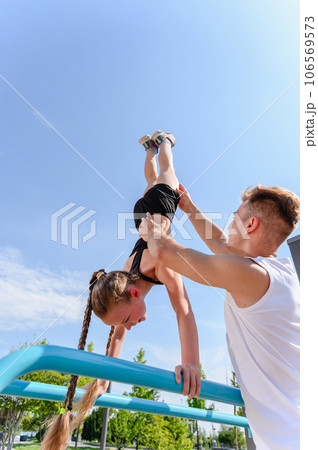 Girl doing hand stand push ups exercise in parallel bars Girl doing hand stand push ups exercise in parallel bars 106569573