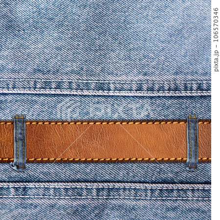Blue denim background with leather belt. Horizontal or vertical backdrop with light blue color denim jeans fabric texture and brown leather strap. Copy space for text Blue denim background with leather belt. Horizontal or vertical backdrop with light blue color denim jeans fabric texture and brown leather strap. Copy space for text 106570346
