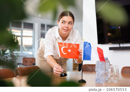 Employee of delegation prepares negotiating table - sets up flag of Turkey and France Employee of delegation prepares negotiating table - sets up flag of Turkey and France 106570553
