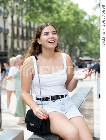 Cheerful girl sitting on La Rambla street during walk through summer Barcelona Cheerful girl sitting on La Rambla street during walk through summer Barcelona 106570699