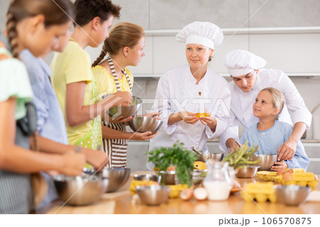 Two friendly chefs giving culinary lesson to group of tweens 106570875