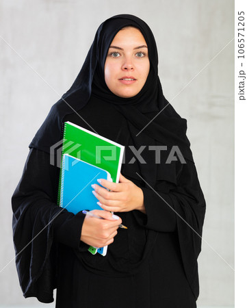 Young student woman dressed in traditional islamic clothes holding notebooks 106571205