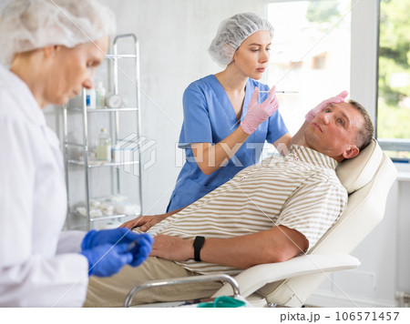 Man applying rejuvenating treatments by female doctor. 106571457