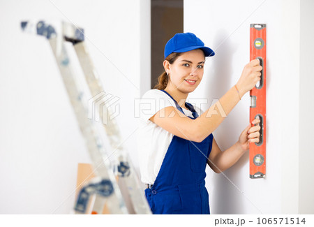 Woman worker measuring wall with spirit level 106571514