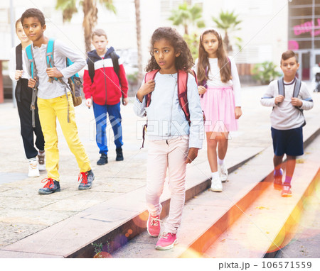 Preteen schoolchildren with backpacks going to college in autumn day Preteen schoolchildren with backpacks going to college in autumn day 106571559
