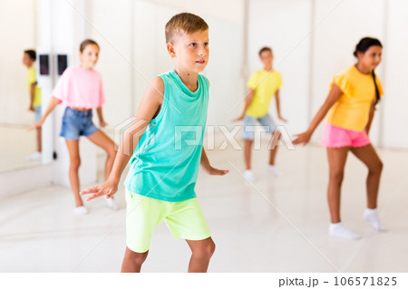 Concentrated tween boy learning charleston during group dance class Concentrated tween boy learning charleston during group dance class 106571825