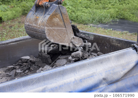 舗装工事イメージ　撤去した古いアスファルトをトラックに乗せるショベルカー 106571990