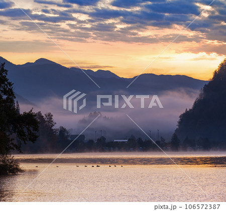 Peaceful autumn Alps mountain lake. Sunrise Wolfgangsee lake view, St. Wolfgang im Salzkammergut, Upper Austria. Peaceful autumn Alps mountain lake. Sunrise Wolfgangsee lake view, St. Wolfgang im Salzkammergut, Upper Austria. 106572387