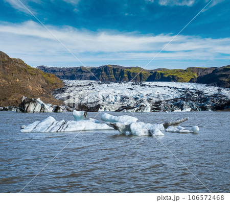 Solheimajokull picturesque glacier in southern Iceland. The tongue of this glacier slides from the volcano Katla. Beautiful glacial lake lagoon with blocks of ice and surrounding mountains. Solheimajokull picturesque glacier in southern Iceland. The tongue of this glacier slides from the volcano Katla. Beautiful glacial lake lagoon with blocks of ice and surrounding mountains. 106572468