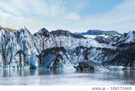 Solheimajokull picturesque glacier in southern Iceland. The tongue of this glacier slides from the volcano Katla. Beautiful glacial lake lagoon with blocks of ice and surrounding mountains. Solheimajokull picturesque glacier in southern Iceland. The tongue of this glacier slides from the volcano Katla. Beautiful glacial lake lagoon with blocks of ice and surrounding mountains. 106572469
