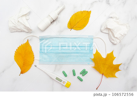 Autumn seasonal cold and illness. Pills, medical mask, nose spray and thermometer. Marble background. Top view. Flat lay. Care and health and treatment plan. 106572556