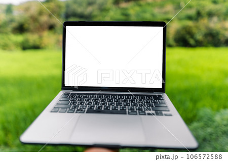 Laptop computer blank screen on a wooden terrace in the background of rice fields Laptop computer blank screen on a wooden terrace in the background of rice fields 106572588