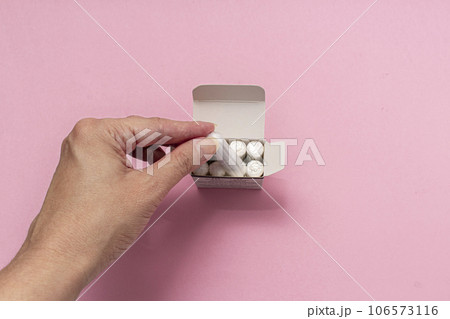 The concept of feminine hygiene, tampons on a pink background. Woman's hand holding a white tampon The concept of feminine hygiene, tampons on a pink background. Woman's hand holding a white tampon 106573116