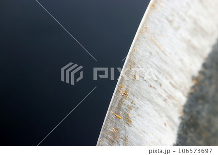 木片が付着する使用感のある斧の刃（黒い背景に曲線を描く刃先のマクロ接写画像） 106573697