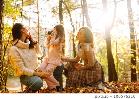 The homosexual family playing with her daughter in the autumn forest. The adventure is more fun. 106576210