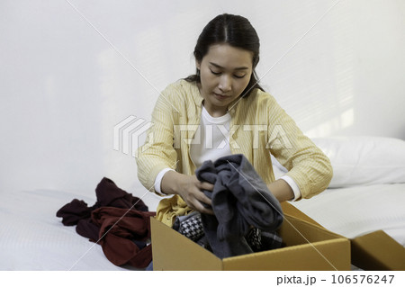 women folded packing clothes into donation box. female volunteering clothes in cardboard box. 106576247
