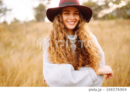 Stylish woman in sweater and hat enjoys autumn nature. People, freedom, lifestyle, travel concept. Stylish woman in sweater and hat enjoys autumn nature. People, freedom, lifestyle, travel concept. 106576904