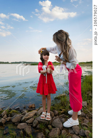 Mom and little daughter walking by the lake or pond Mom and little daughter walking by the lake or pond 106579027