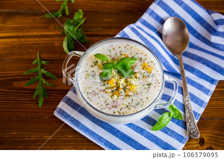 Cold soup with cucumbers, eggs, vegetables, yogurt and fresh herbs in a glass bowl . 106579095