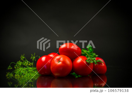 Ripe red tomatoes with greens on black background. 106579138