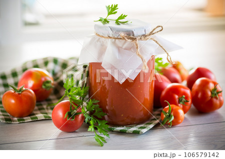 Cooked homemade tomato juice canned in a jar of natural tomatoes. Cooked homemade tomato juice canned in a jar of natural tomatoes. 106579142