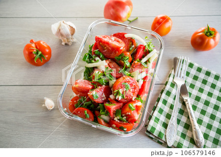 Spicy snack tomatoes with garlic, herbs, seasonings and onions in a glass bowl . 106579146