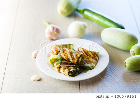 Grilled zucchini pieces with garlic sauce in a white plate. 106579161