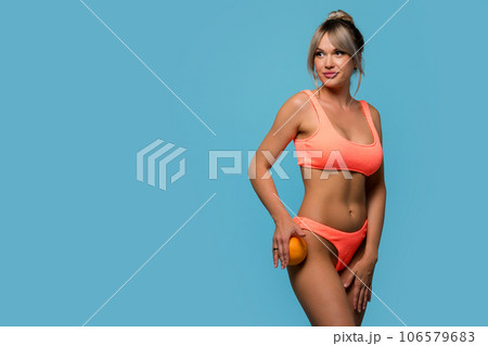Slim woman wearing swimsuit posing with sweet orange Slim woman wearing swimsuit posing with sweet orange 106579683