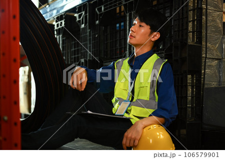 Tired man warehouse worker in jacket leaning against shelve while having short break 106579901