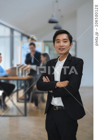 Young asian businessperson working at office and crossed arms with employees in the background 106580128