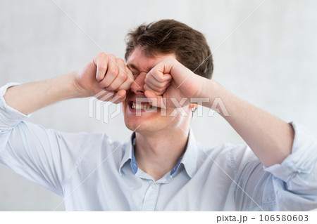 Man scretching itchy eyes on gray background 106580603