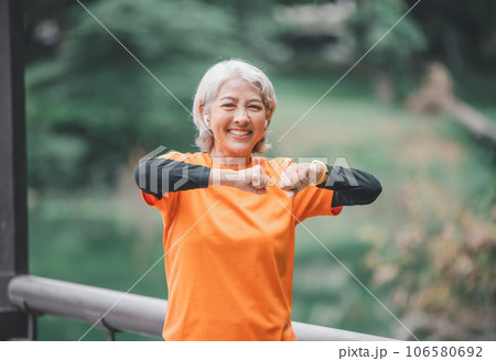 white-haired elderly person exercising in the park early in the morning. 106580692