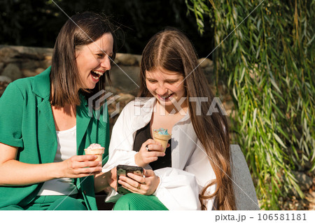 Mom and teenage daughter eat ice cream on walk Mom and teenage daughter eat ice cream on walk 106581181